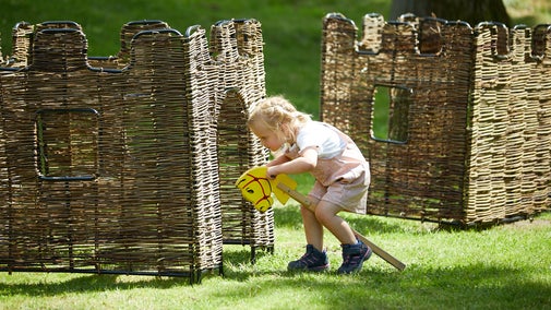 Child playing with a hobby horse and castles
